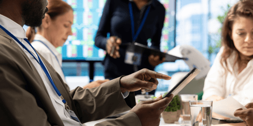 A group of colleagues reviewing data on a tablet during a meeting.
