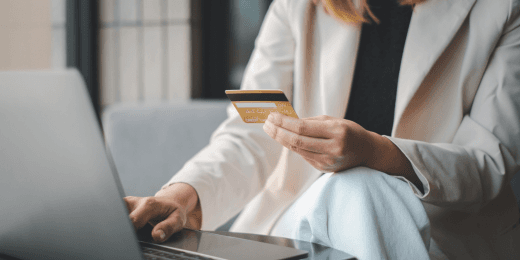 Person holding a credit card while using a laptop for an online transaction.