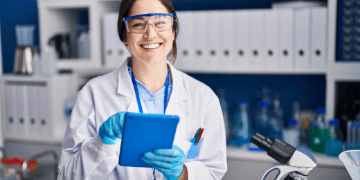 A doctor, wearing a face mask and holding a tablet, is smiling.