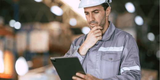 Man in PPE holding a tablet thinking