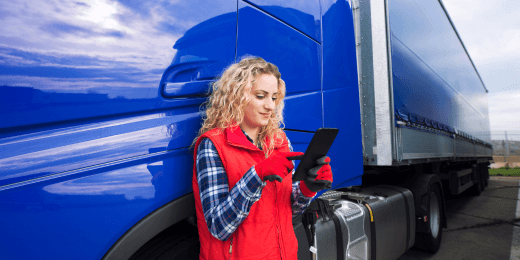 Woman using a tablet beside a blue heavy vehicle truck