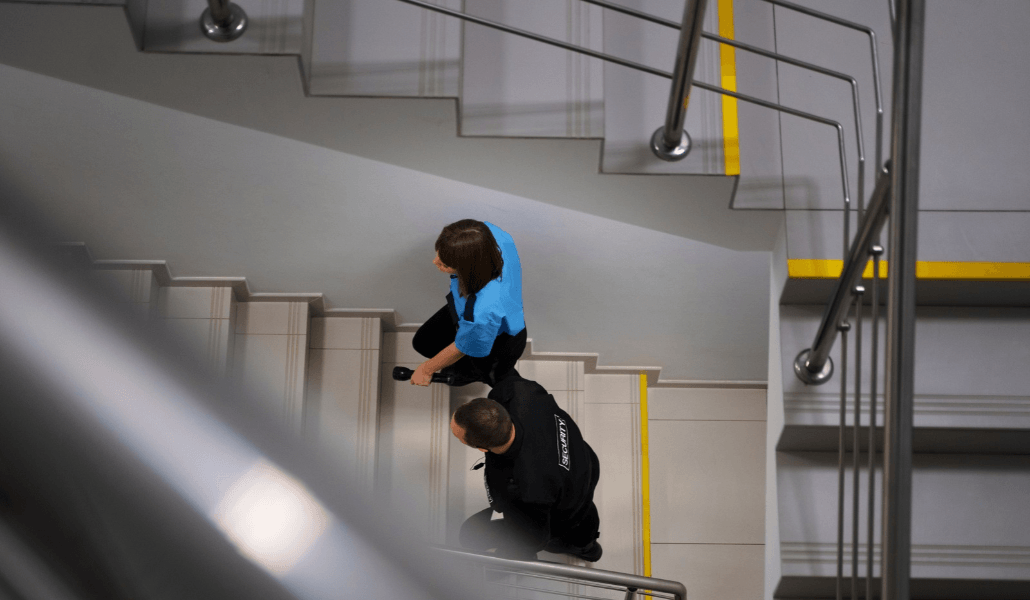 Security guards going up a flight of stairs with yellow safety markings.