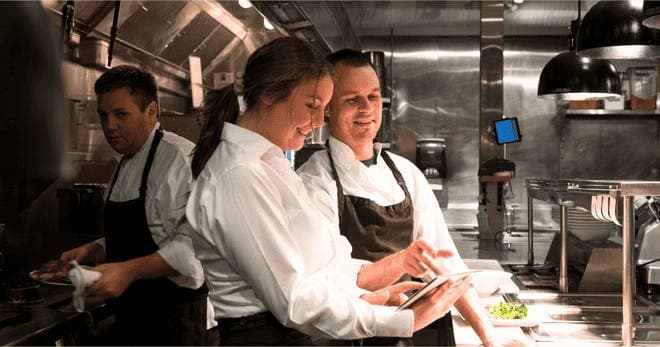 Restaurant manager and chef discusses menu options on a digital tablet