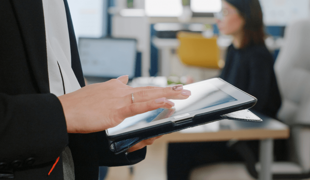 Person using a tablet in an office setting, referencing WHS compliance information.