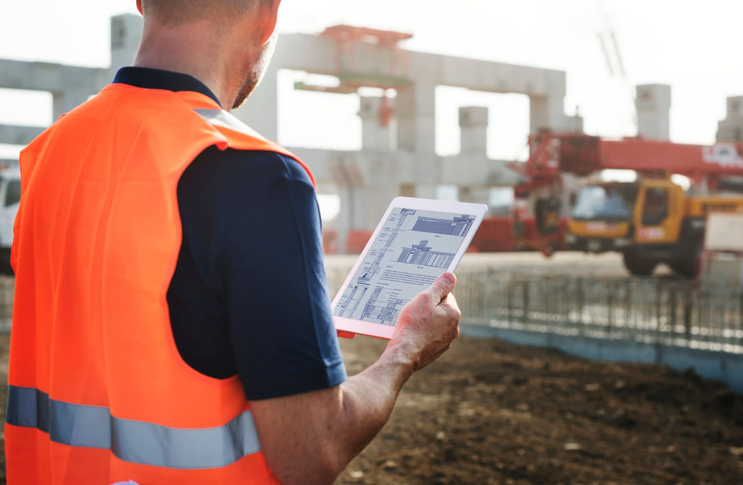 ein Bauingenieur, der eine Inspektion am Standort mit Hilfe einer Projektmanagement-Software für Unternehmen auf einem Tablet durchführt