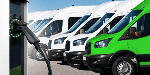 A charging station in front of a fleet of electric delivery vans.