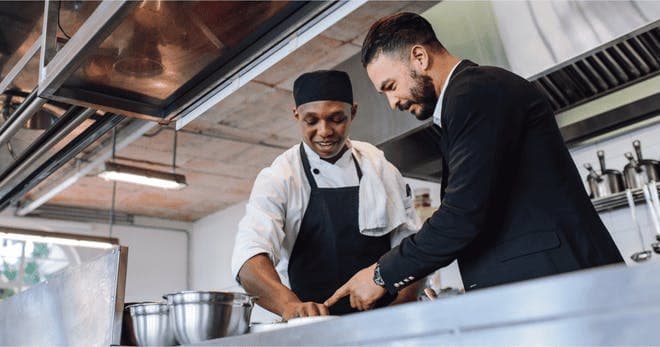 Restaurant manager discussing with chef in kitchen