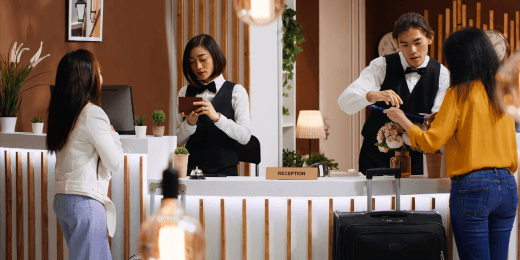 Hotel reception staff assisting two guests at the front desk.